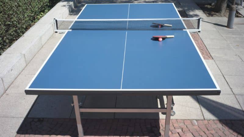 Blaue Tischtennisplatte steht draußen aufgebaut